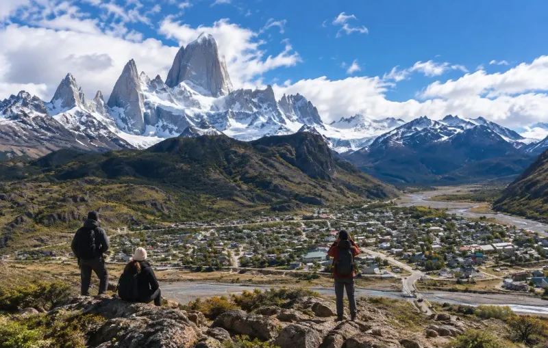 Viajeros en un mirador con el cerro Fitz Roy y el pueblo de El Chaltén de fondo